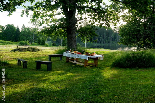 Wooden table under oaks with many traditional Latvian food. Old Latvian culture tradition LIGO. Midsummer night celebrating in Latvia. 