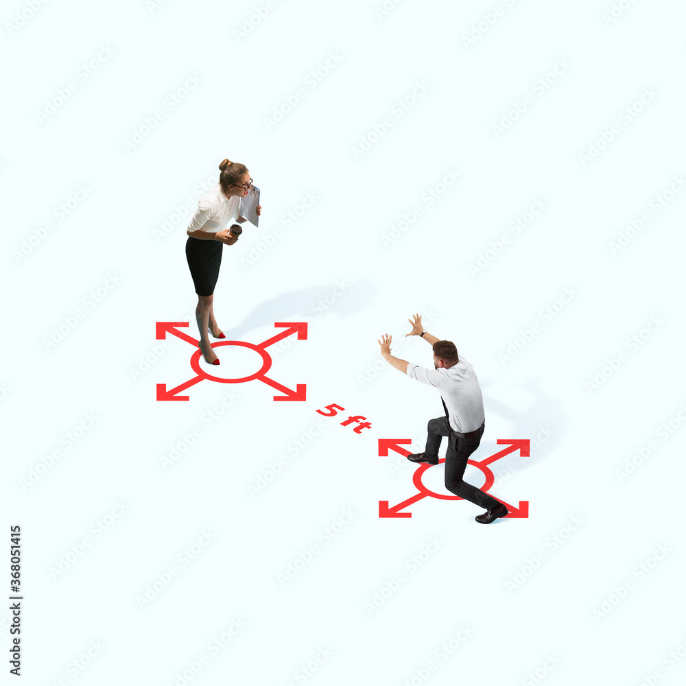 Studio shot of people demonstrating social distancing with arrows indicating the separation. Office workers during coronavirus outbreak with new rules for safety and healthcare. High angle view