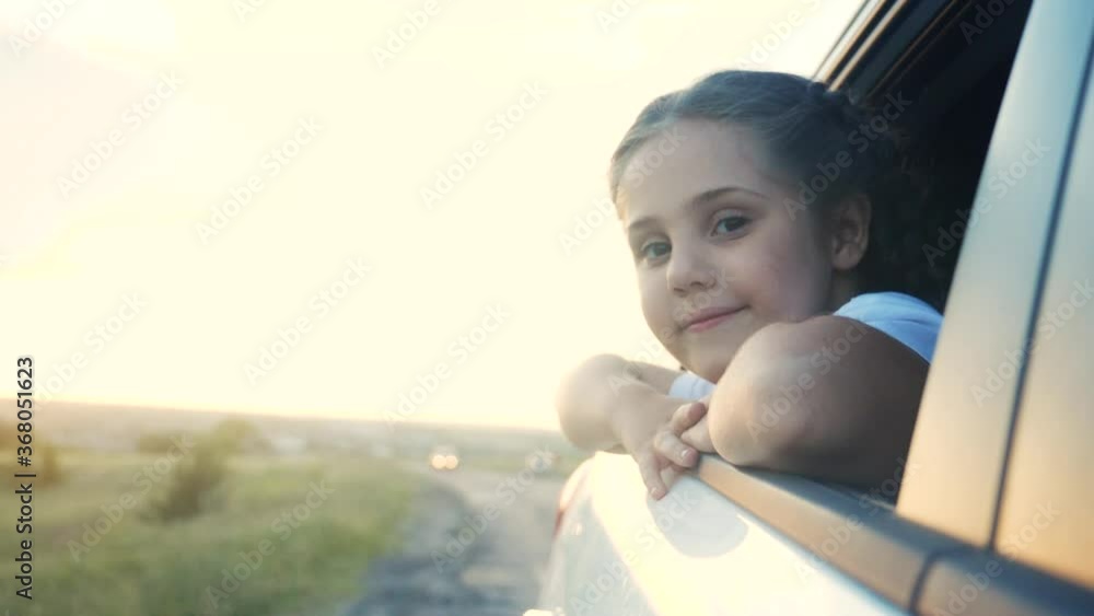happy girl kid child smile leaned out of a car window waving hand. happy family travel journey concept. daughter sister looks out of a car window. little happiness girl drive lifestyle road to happy girl kid child smile leaned out of a car window waving hand. happy family travel journey concept. daughter sister looks out of a car window. little happiness girl drive lifestyle road to