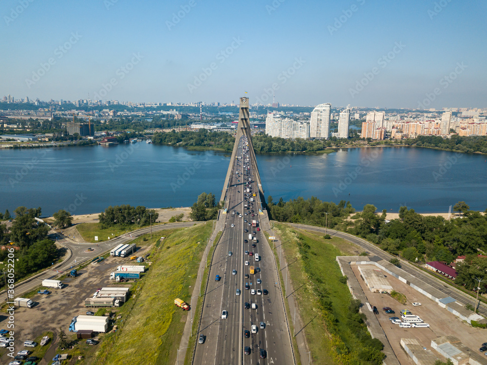 Aerial drone view. Cars travel along the North Bridge over the Dnieper River in Kiev. Summer sunny day.