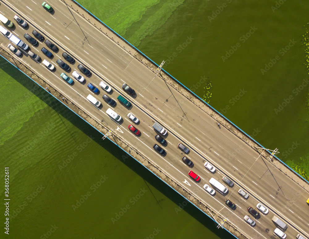 Cars travel along the North Bridge over the Dnieper River in Kiev. Summer sunny day, green algae bloom in the water.