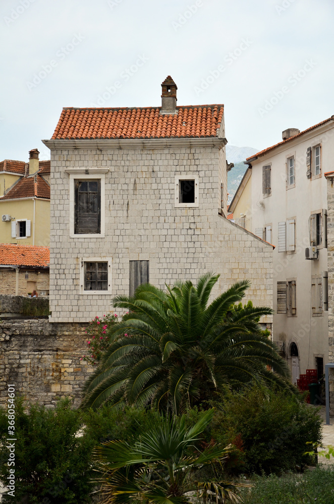 a cozy corner of old Europe with a stone building and palm trees nearby