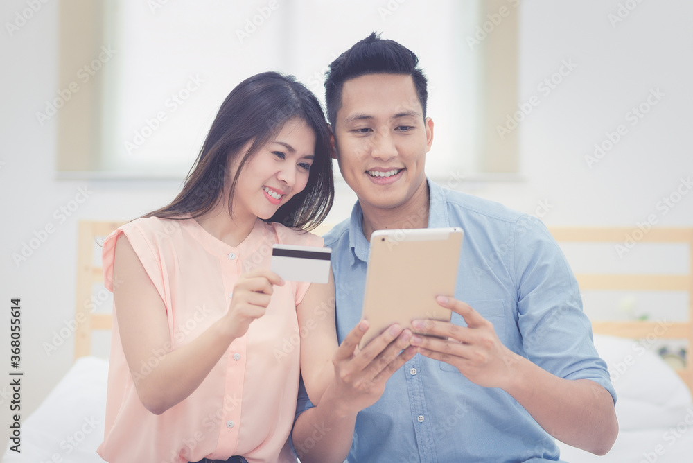 Happy Family,Asian couple lovers enjoy using smart tablet for online shopping together in bedroom.Photo series of family and happy people concept. Happy Family,Asian couple lovers enjoy using smart tablet for online shopping together in bedroom.Photo series of family and happy people concept.