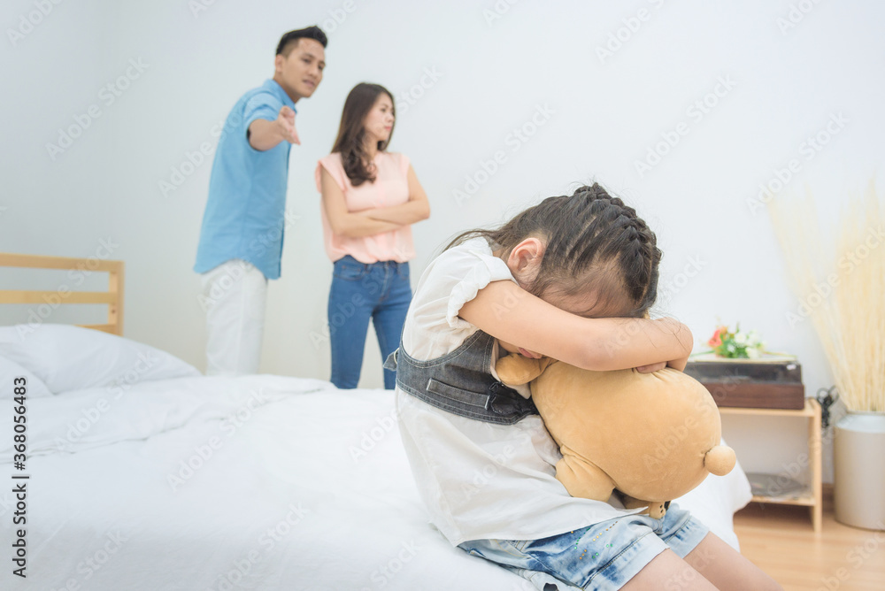 Asian little girl sadness while parent quarrelling in bedroom.Photo design for family problems and unhappy concept. Asian little girl sadness while parent quarrelling in bedroom.Photo design for family problems and unhappy concept.