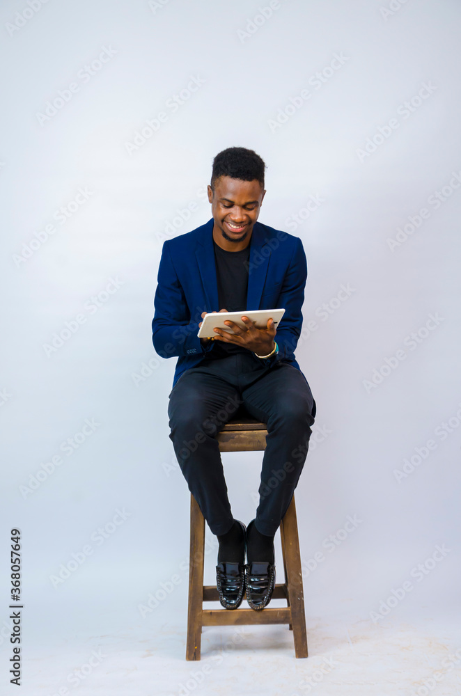 a young handsome african businessman isolated over white background smiles as he holds his tablet a young handsome african businessman isolated over white background smiles as he holds his tablet