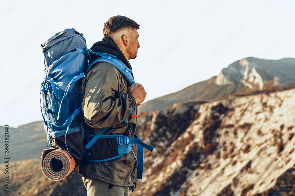 Young caucasian man traveler with big backpack hiking in the mountains Photos Adobe Stock