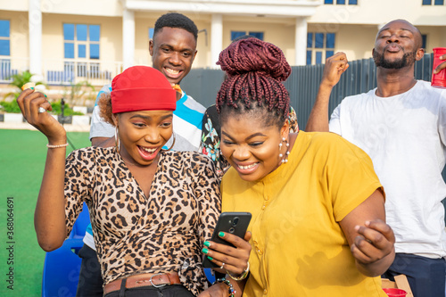 two young african ladies check their phone and get excited photo