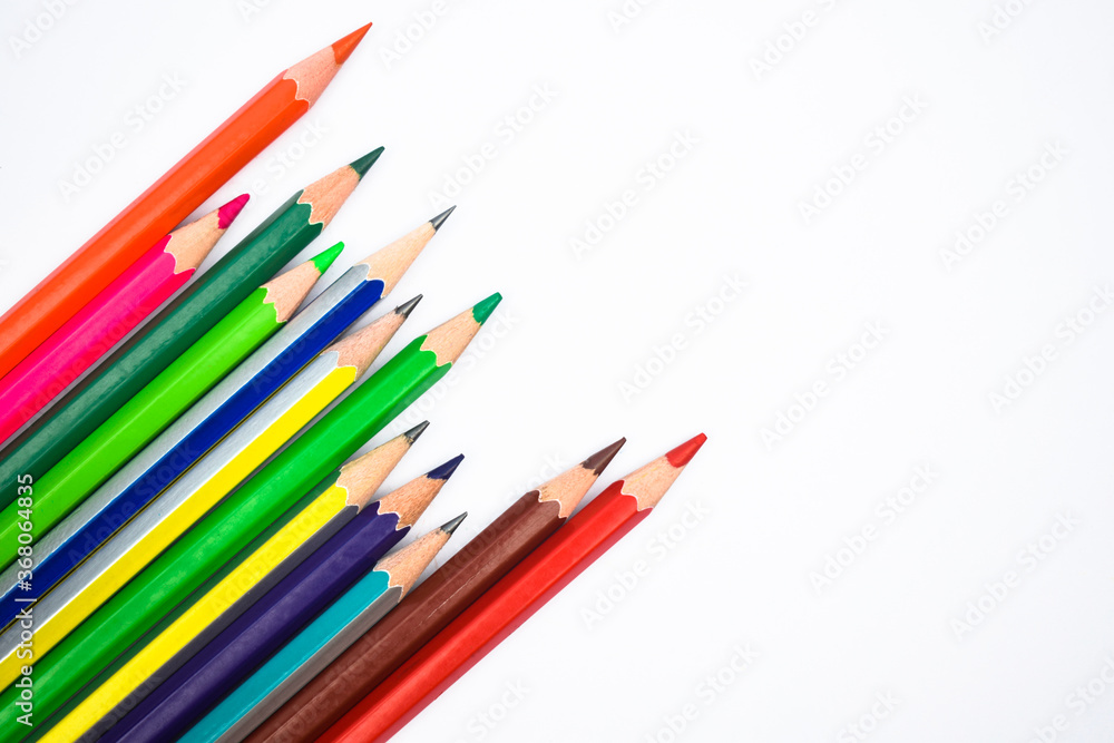 Lot of different colored wood pencil crayons scattered across a white background