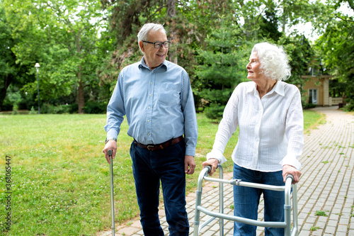 Bild auf Leinwand Elder people using walking cane and a walker for a gentle stroll in the park