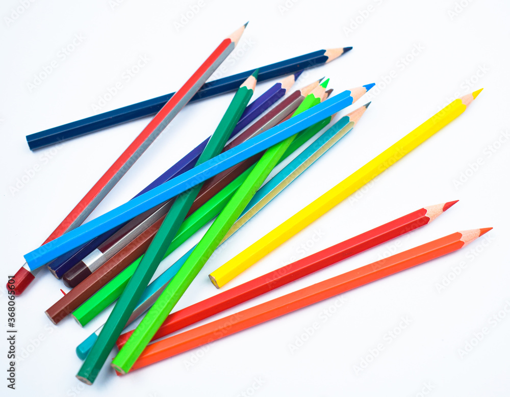 Some different colored wood pencil crayons scattered across a white background