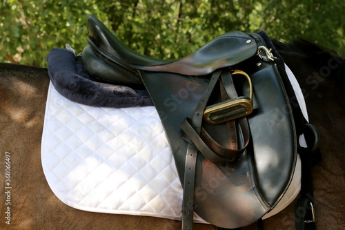 Fototapeta Naklejka Na Ścianę i Meble -  Photo of old leather saddle with stirrups