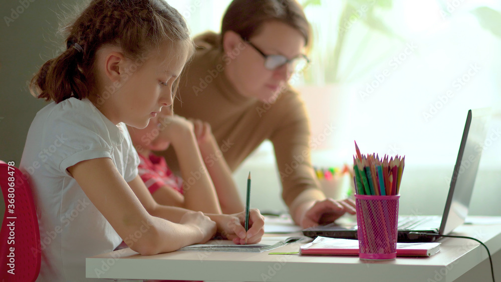 Cute children use laptop for education, online study, home studying, Boy and Girl have homework at distance learning. Lifestyle concept for home schooling. Mother helps daughter and son. Cute children use laptop for education, online study, home studying, Boy and Girl have homework at distance learning. Lifestyle concept for home schooling. Mother helps daughter and son.