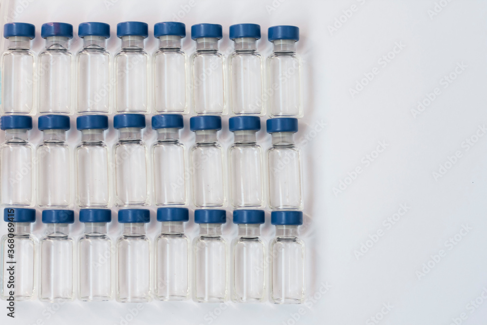 Glass medicine bottles with injection fluid with blue aluminium caps and syringe for vaccination. Cancer, painand diabetestreatment, pharmaceutical medicine concept. Glass medicine bottles with injection fluid with blue aluminium caps and syringe for vaccination. Cancer, painand diabetestreatment, pharmaceutical medicine concept.