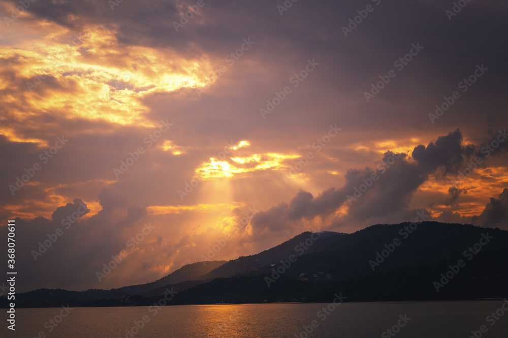 Beautiful landscape, dark dramatic clouds, sunshine and bright sunset sky over the sea