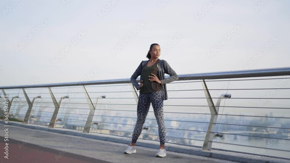 extra long shot. A girl African American athlete stands on a glass bolkon and does exercises for the legs and hip joint. 4K extra long shot. A girl African American athlete stands on a glass bolkon and does exercises for the legs and hip joint. 4K