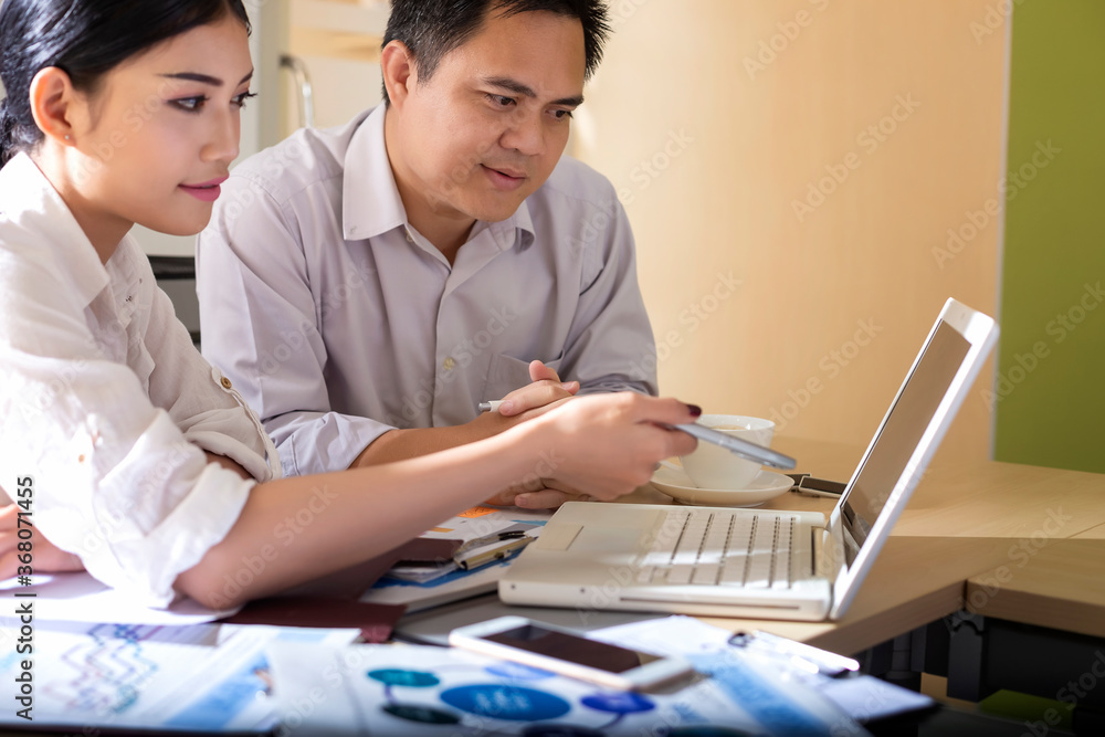 Young businessmen are sitting in a meeting to analyze data from computers and graph paper to make investment decisions. Young businessmen are sitting in a meeting to analyze data from computers and graph paper to make investment decisions.