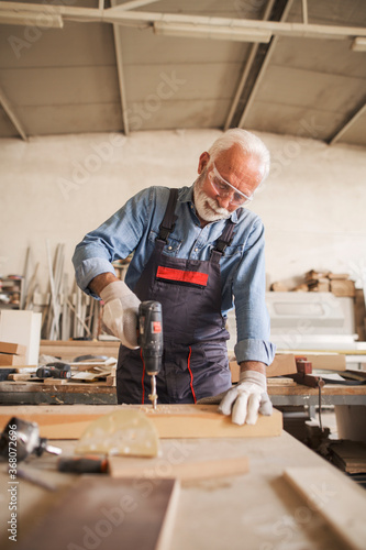 Obraz na plátne Waist up portrait of a carpenter drilling