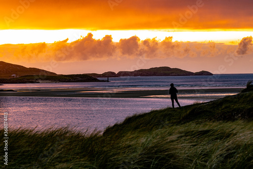 Girl silhouetted against a sunset on the Wild Atlantic Way in Gweedore, County Donegal, Ireland. photo