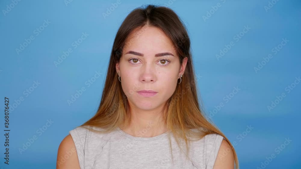 Guilty woman in gray t-shirt nods head and says yes on blue background with copy space. 4K slow motion footage Guilty woman in gray t-shirt nods head and says yes on blue background with copy space. 4K slow motion footage