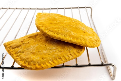 Quadro su tela two Jamaican patties on a wire rack isolated on white
