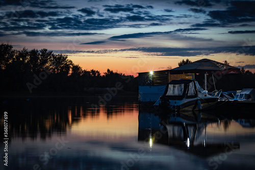 Sunset on the Volga river. View of one of the islands on the Volga river from the shore during sunset and the boat at the pier.