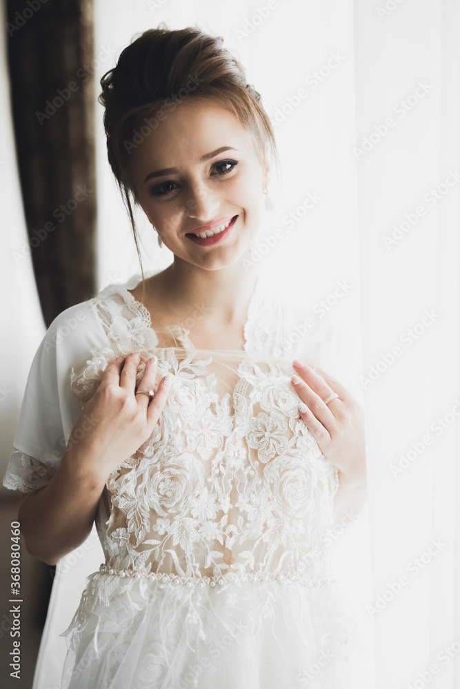 Gorgeous bride in robe posing and preparing for the wedding ceremony face in a room Gorgeous bride in robe posing and preparing for the wedding ceremony face in a room