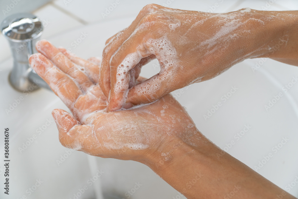 Fototapeta premium Hands of girl use soap and washing under the water tap. Hygiene concept hand detail. woman washing hands with soap over sink in bathroom.