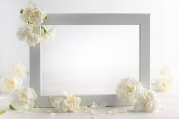 Still life with white flowers and frame on light backdrop. Creative concept for celebration of mother day, birthday, wedding or Valentines day