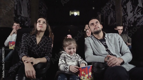 Young man and woman with a child are watching a movie.