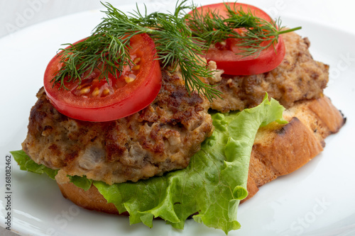 sandwich with cutlets lettuce and tomato slices on white background