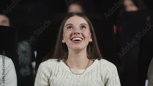 Quadro su tela A young woman at the movies begins to smile and laugh