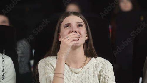 Foto Close up of a scared young woman using her hands to cover her face while watching a scary movie