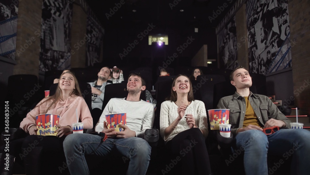 Young people laugh at comedy movie in cinema theatre. Young people laughing at cinema watching amusing comedy.