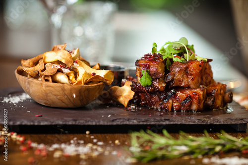 Pork ribs cooked at low temperature. Blackcurrant sauce, parsnip chips with Parmesan cheese. Delicious healthy meat food closeup served on a table for lunch in modern cuisine gourmet restaurant
