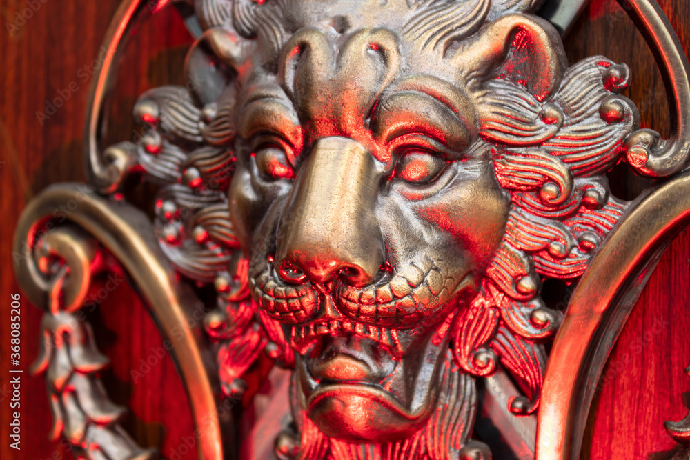 Close up to a golden Iron Lion shiled iluminated with red light. Interior design, ornaments and welding concept