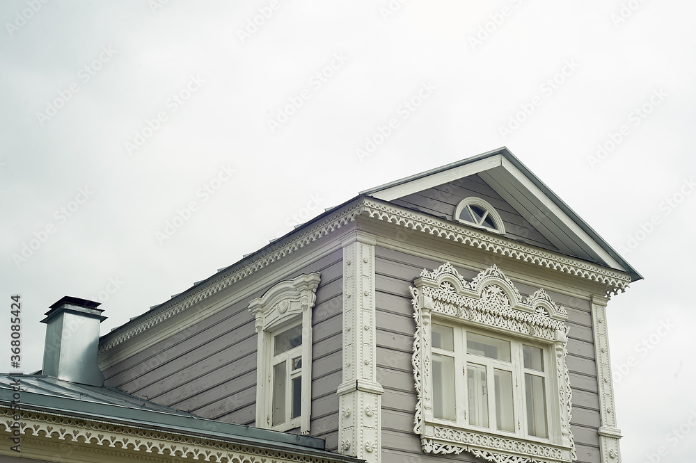 Mansard of an old wooden house with tiles.A roof with a metal pipe. An old Russian village.