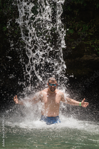 man bathing in a national park waterfall in the jungle of el Yunque national park in puerto rico 