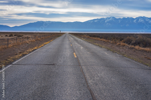 The road goes to the horizon against the background of the morning cloudy sky and mountains