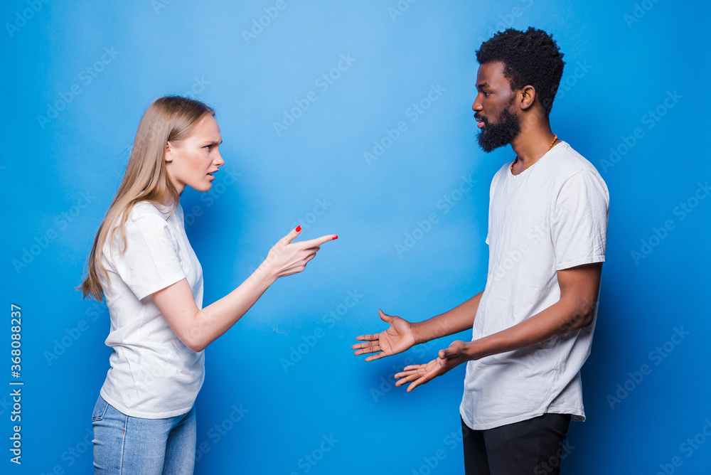 Young mixed couple quarrel isolated on blue background Young mixed couple quarrel isolated on blue background