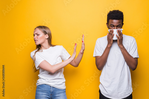 Young diverse couple, man sneeze women shocked isolated on yellow background studio. Epidemic pandemic photo