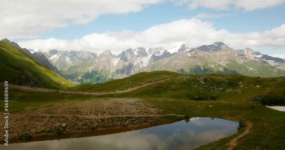 Hike on Calm Lake Koruldi Lakes in Mestia Green Fresh Highlands Hill with Beautiful Amazing Landscape of Caucasus Mountains with Snow and Blue Sky With Clouds as Nature Mirror Reflection Hike on Calm Lake Koruldi Lakes in Mestia Green Fresh Highlands Hill with Beautiful Amazing Landscape of Caucasus Mountains with Snow and Blue Sky With Clouds as Nature Mirror Reflection