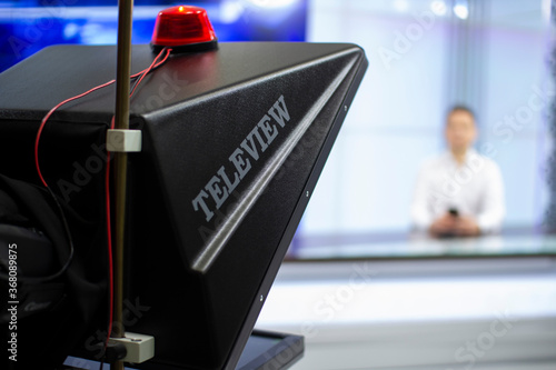 A male News anchor in a broadcast Studio reads text on a teleprompter. Camera in the TV Studio.