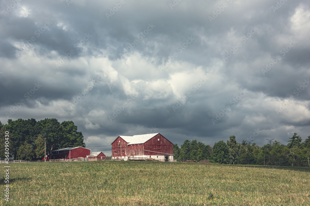 Red rural barn with heavy cumulus clouds overhead. Red rural barn with heavy cumulus clouds overhead.