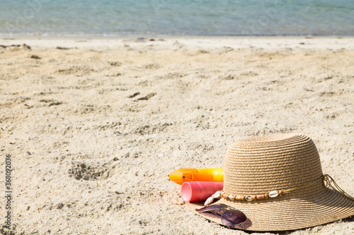 hat, sunglasses and suntan lotion on the beach, summer vacation accessories