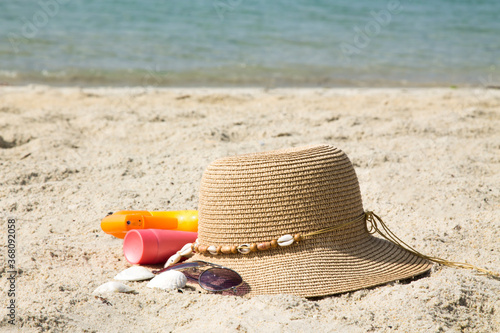 hat, sunglasses and suntan lotion on the beach, summer vacation accessories