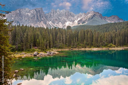 Lake Carezza an alpine lake surrounded with tall pine forest in the Dolomites with Rosengarten mountain range view background in South Tyrol, Italy