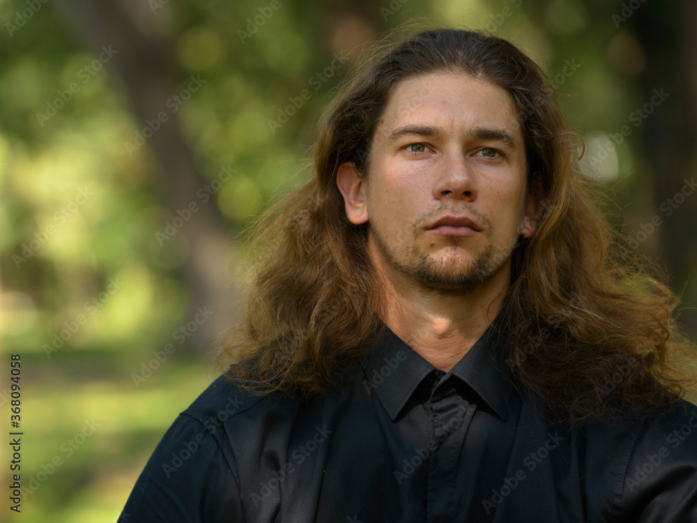 Handsome bearded businessman with long hair at the park Handsome bearded businessman with long hair at the park