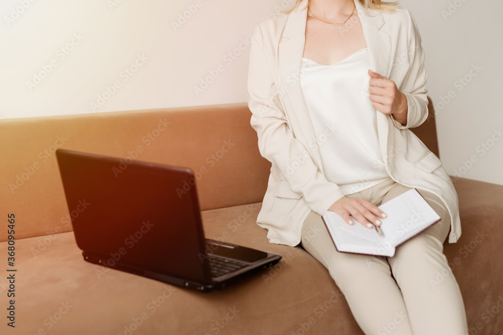 Naklejka premium The businesswoman with a laptop sitting on the sofa