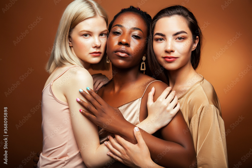 Obraz premium young pretty asian, caucasian, afro woman posing cheerful together on brown background, lifestyle diverse nationality people concept