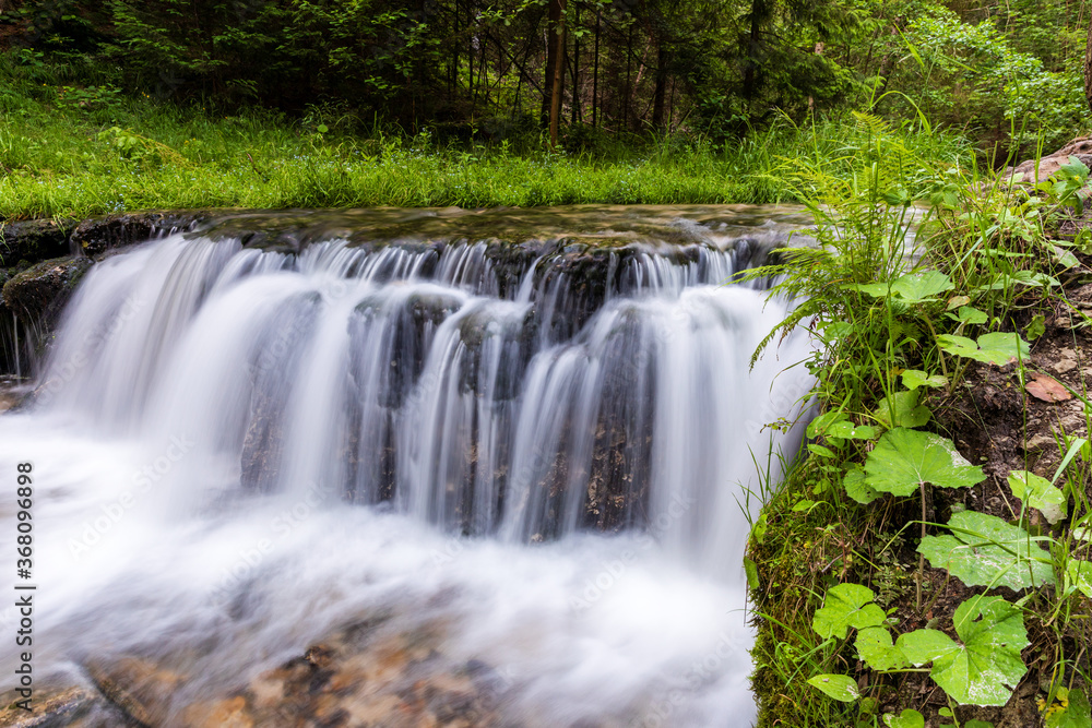 Smooth abstract water cascade at Jelen wild river. Nature water landscape. Landscape park Solska forest at Roztocze, Poland, Europe. Smooth abstract water cascade at Jelen wild river. Nature water landscape. Landscape park Solska forest at Roztocze, Poland, Europe.